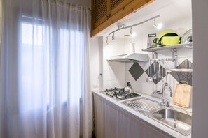 A kitchen with a gas stove, stainless steel sink, and a wooden cutting board.