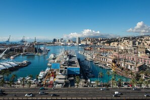 Uma marina com barcos atracados, uma grande roda-gigante e um horizonte urbano ao fundo.