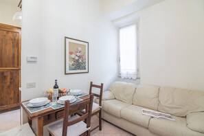 A dining area with a wooden table, chairs, and a beige sofa.