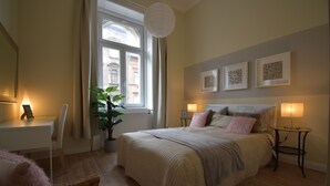 Une chambre à coucher avec un grand lit, une plante en pot, un bureau et une chaise.