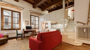 Un salon chaleureux avec un canapé rouge, un plancher en bois et un escalier menant à l’étage supérieur.