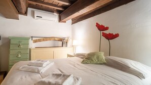 Une chambre à coucher avec un lit, une commode verte, une tête de lit en bois et un climatiseur fixé au mur.