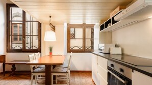 Une cuisine avec une table en bois, des chaises, un poêle et une fenêtre donnant sur un beau paysage.