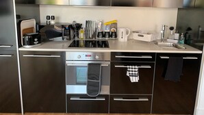 Een moderne keuken met roestvrijstalen apparatuur, een inbouwoven en een koffiezetapparaat.