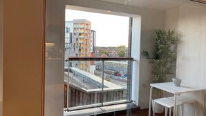 Een moderne kamer met een groot raam, een klein tafeltje en een plant in pot.
