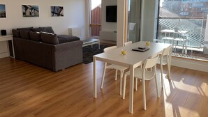 Een moderne woonkamer met een bank, een eettafel met stoelen, een televisie en kunst aan de muur.