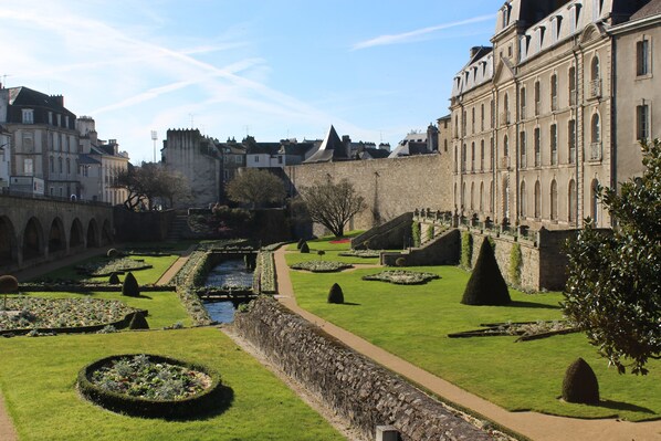 A historic courtyard with a central water feature, surrounded by well-manicured gardens and stone walls. - Intramural residence "Porte Poterne" in Vannes (Vannes)