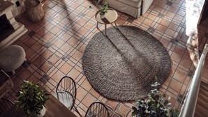 Ein rustikaler Raum mit Steinwänden, einem weißen Sofa, gewebten Teppichen und hängenden Korblampen.
