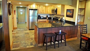 A kitchen with wooden cabinets, a refrigerator, a microwave, and a large island with stools. - Best Ski-in/Ski-Out Condo at Copper Mountain - Sleeps 8! (Copper Mountain)