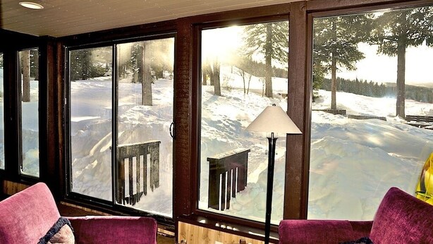 A room with large windows offering a snowy outdoor view, a wooden deck, and a lamp. - Best Ski-in/Ski-Out Condo at Copper Mountain - Sleeps 8! (Copper Mountain)