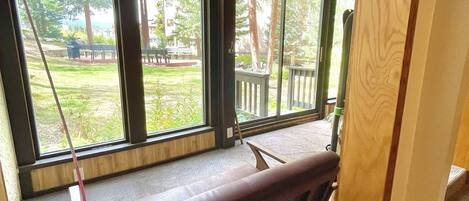 A room with a large window, a bench, and a view of a garden and trees.