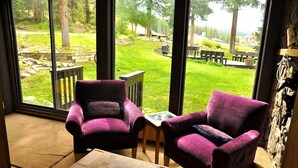 A room with two purple armchairs, a small table, and a large window offering a view of a grassy outdoor area with trees and a picnic table. - Best Ski-in/Ski-Out Condo at Copper Mountain - Sleeps 8! (Copper Mountain)
