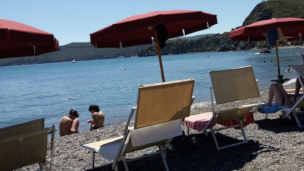 Une plage avec des parasols rouges et des chaises longues.