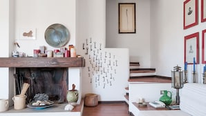 Une pièce avec une cheminée, des clés accrochées au mur, des tableaux encadrés et un vase vert.
