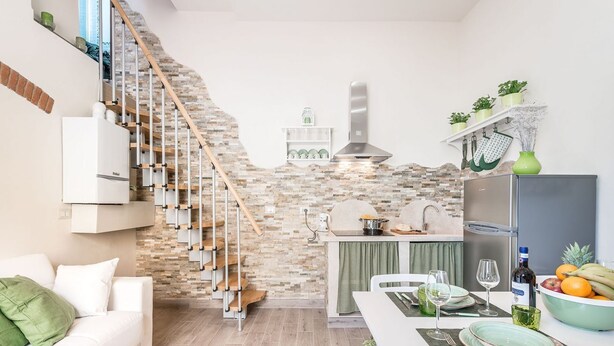 A modern kitchen with a stone backsplash, a built-in stove, and a refrigerator. - Apartment Dreamy Guelfa by Mmega (Firenze)