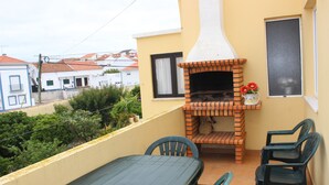 Ein Balkon mit Backofen, Tisch und zwei Stühlen.
