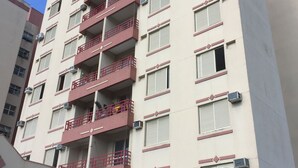 A multi-story building with balconies, air conditioning units, and a clear blue sky. - Beach apartment in Enseada, in a gated community, with garden and balcony. (Guaruja)