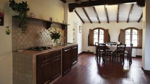 Una cocina con alacenas de madera oscura, salpicadero de azulejos y una zona de comedor con mesa y sillas.