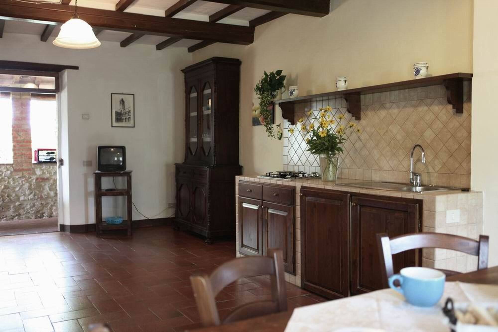 Una cocina con armarios de madera oscura, un salpicadero de azulejos y una estufa empotrada. Hay un comedor con una mesa y sillas.