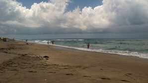 A beach with a sandy shore and waves, under a cloudy sky. - Roonie's Periwinkle Cottage -  waterfront- 2 bikes - downtown Stuart (Stuart)