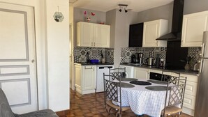 Une cuisine compacte avec des meubles blancs, un pare-feu en carrelage et un coin repas comprenant une table et des chaises.