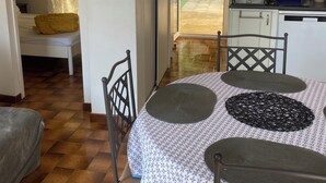 Une pièce confortable comprenant une table à manger, des chaises, un lit et un coin cuisine.