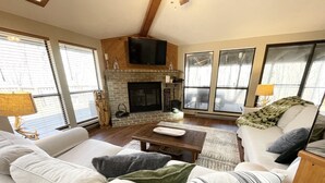 A living room with a fireplace, a sofa, a coffee table, and a television mounted on the wall.