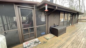 A covered outdoor area with a bench, a welcome mat, and a covered grill.