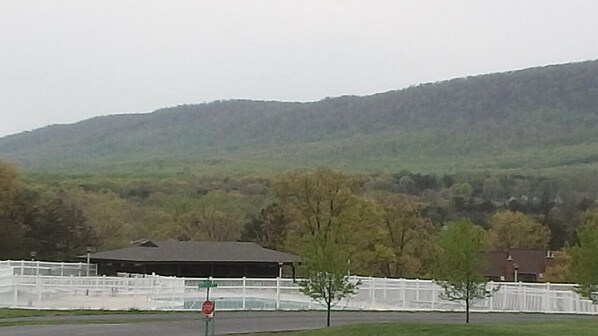 A rural landscape with a white fence, a covered structure, and a road.