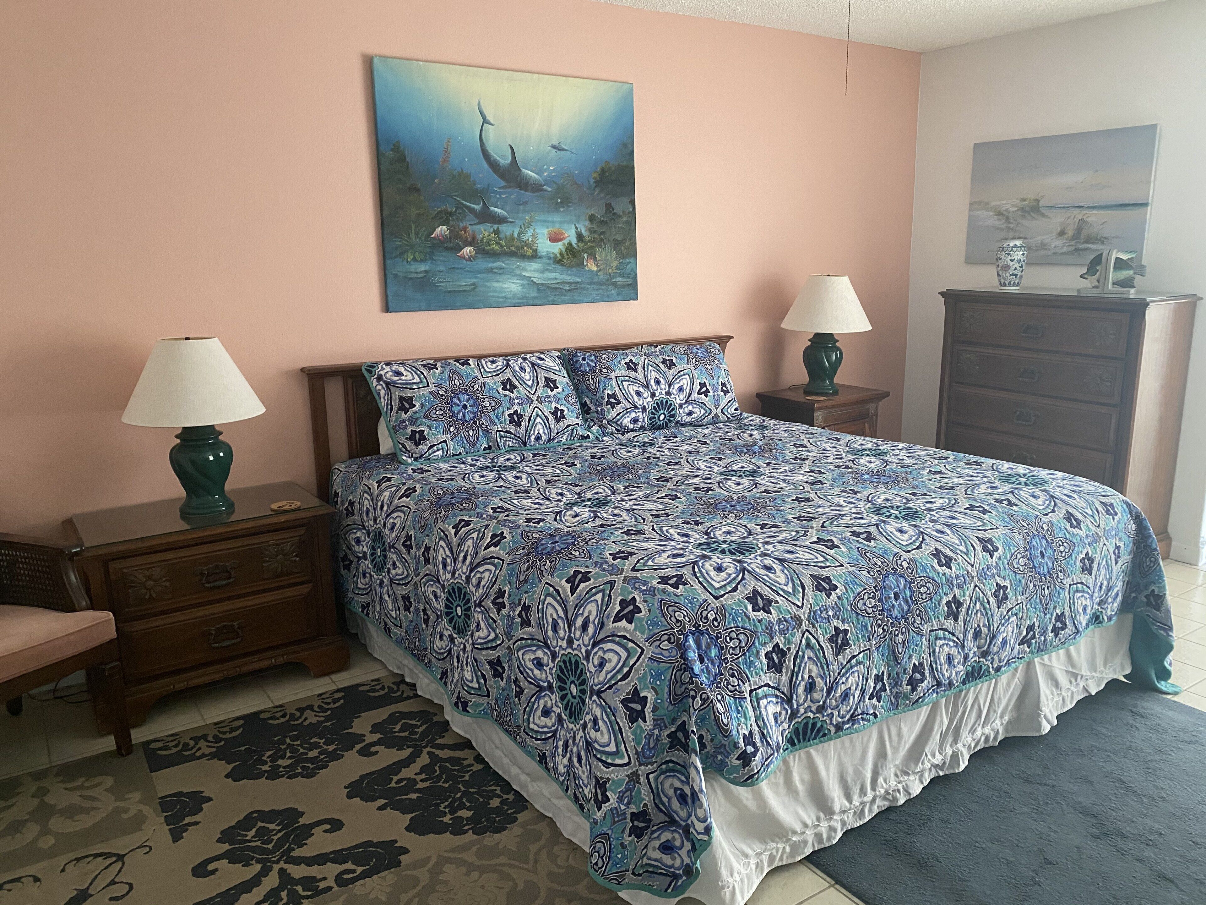 A bedroom with a bed, two bedside tables with lamps, a dresser, and a rug.