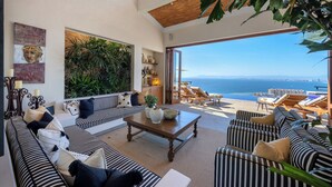 A spacious living area with a large sofa set, a coffee table, and a view of the sea.