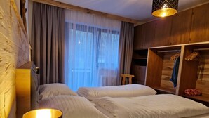 Une chambre à coucher avec un lit, une lampe de chevet, une armoire en bois et une fenêtre avec des rideaux.
