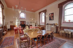A spacious room with a large wooden dining table, multiple chairs, a chandelier, and a fireplace. - Historic Chapel, Great Facilities nr Beaches (St Austell)