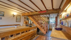 Una cocina rústica con vigas de madera, un banco de madera y una escalera.