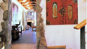 A stone archway leading to a lobby with a wooden ceiling, a stone fireplace, and a large red artwork with Chinese calligraphy. - Ski Chalet Rental in Chile (Santiago)