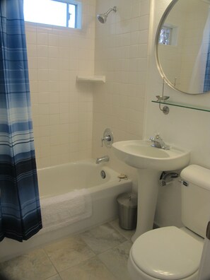 A bathroom with a bathtub, sink, toilet, and a mirror.