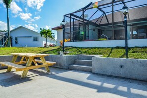 A modern house with a large glass window, a concrete bench, and a small garden. - Coconut Cove / Scenic Waterfront Escape with Private Heated Pool & Spa (Cape Coral)