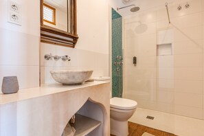 A bathroom with a marble sink, a toilet, and a glass shower enclosure.