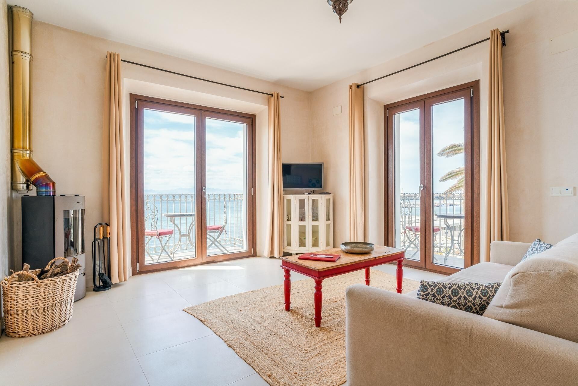 A spacious living room with a large sliding glass door leading to a balcony, a television on a cabinet, and a cozy seating area.