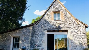 Ein Gebäude aus Stein mit einer großen Schiebeglastür, einem kleinen Fenster und einer Tür.