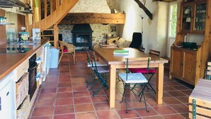 Eine rustikale Küche mit einer Holztreppe, einem Kamin und einer Essecke mit Klappstühlen.