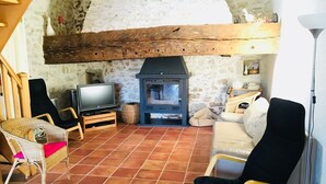 Ein gemütliches Wohnzimmer mit Steinwand, Kamin, Fernseher und bequemen Sitzgelegenheiten.