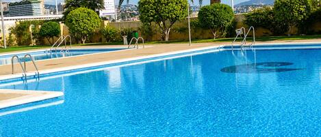 A clear blue swimming pool with a view of a cityscape in the background.