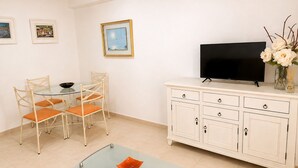 A room with a dining table, chairs, a TV on a cabinet, and a vase with flowers. - Calpe: apartment/ flat - CALPE (Calpe)