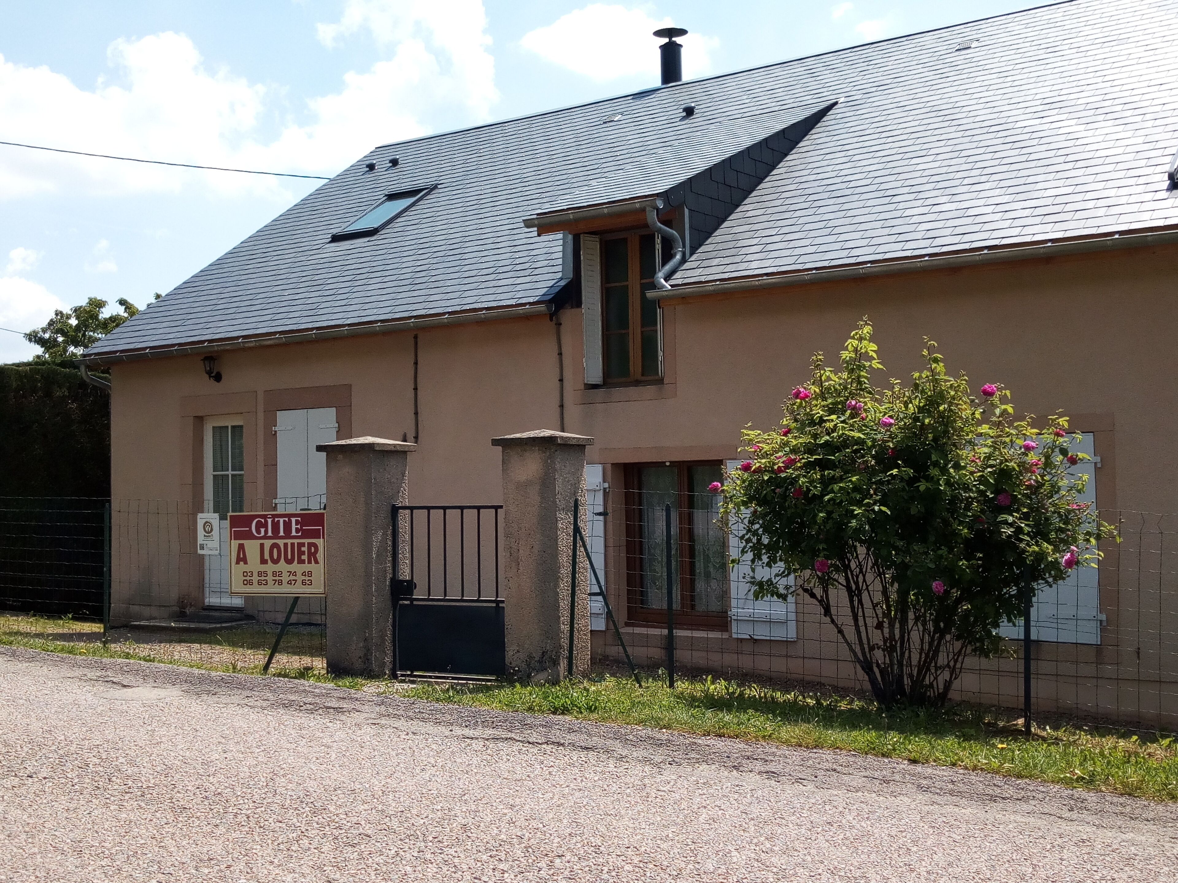 Ein zweistöckiges Gebäude mit geneigtem Dach, einem kleinen Fenster und einem Schild, das ein Geschäft bewirbt.