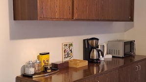 A kitchen counter with a coffee maker, a microwave, and various containers.
