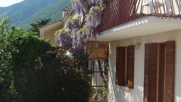 A building with a balcony, a gravel pathway, and a mountain in the background.