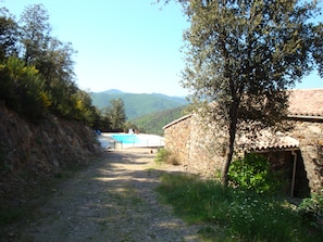 Ein schmaler Feldweg führt zu einem Steinhaus mit einem Pool.