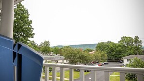 Een balkon met uitzicht op een parkeerplaats en huizen.
