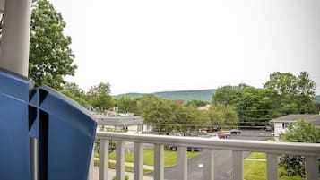 Een balkon met uitzicht op een parkeerplaats en huizen.